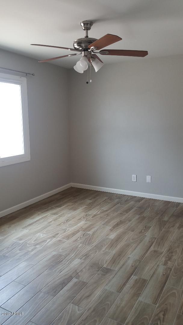 unfurnished room with a ceiling fan, wood finished floors, and baseboards