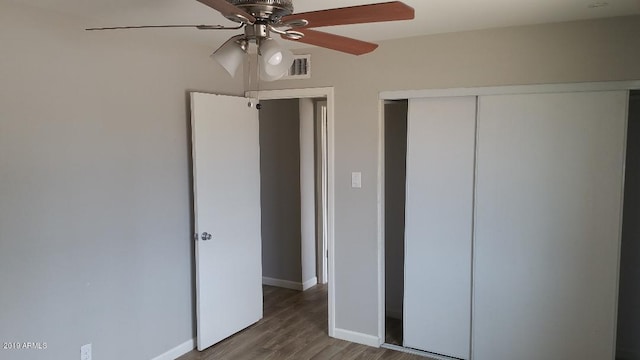 unfurnished bedroom with wood finished floors, baseboards, a closet, and ceiling fan