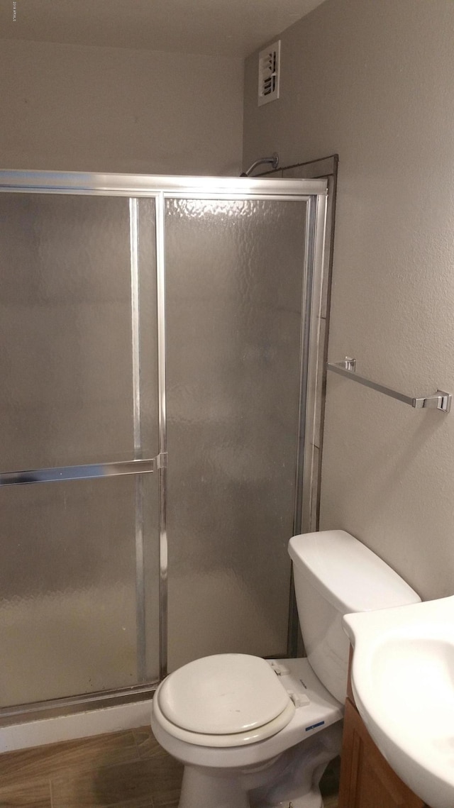bathroom featuring a stall shower, vanity, toilet, and wood finished floors