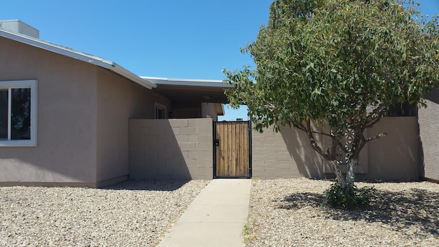 property entrance with a gate, stucco siding, and fence