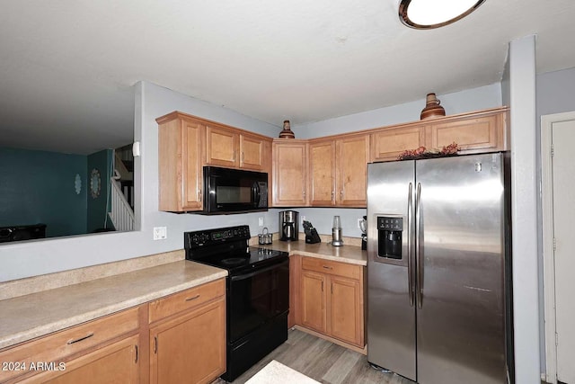 kitchen with black appliances, light wood-style flooring, and light countertops