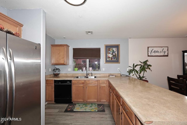 kitchen featuring visible vents, a peninsula, freestanding refrigerator, a sink, and black dishwasher