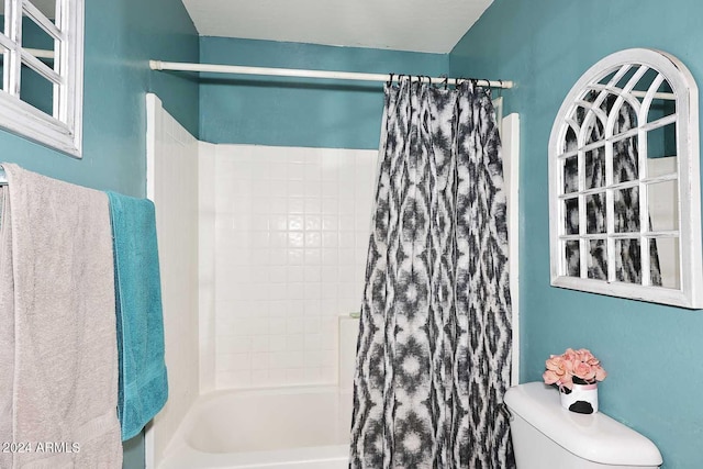 bathroom featuring toilet and shower / bath combination with curtain