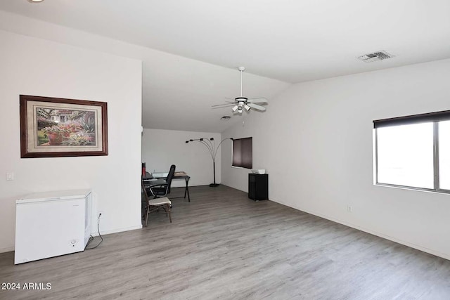 unfurnished living room with a ceiling fan, vaulted ceiling, light wood-style floors, and visible vents