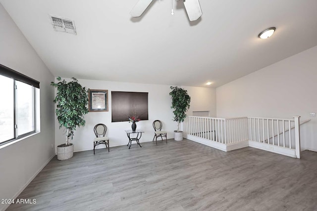 sitting room featuring visible vents, an upstairs landing, lofted ceiling, and wood finished floors