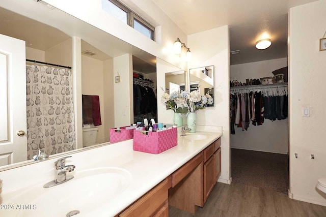 full bath featuring double vanity, toilet, wood finished floors, and a sink