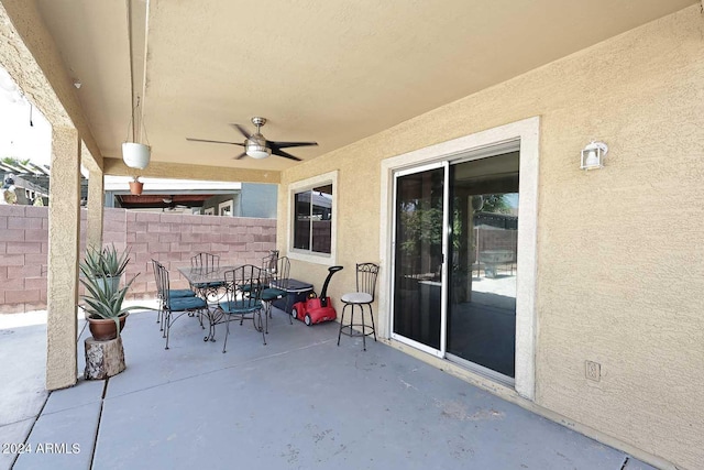 view of patio with outdoor dining area, a ceiling fan, and fence