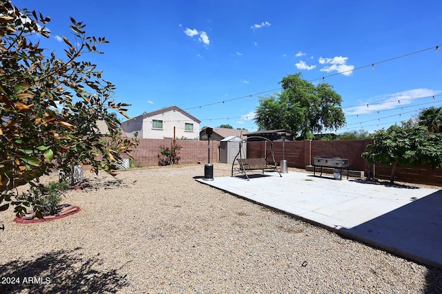 view of yard featuring an outdoor structure, a storage unit, a fenced backyard, and a patio