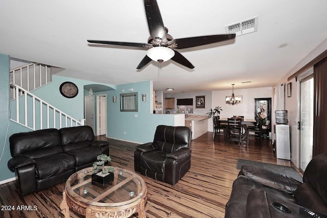 living area with visible vents, ceiling fan with notable chandelier, wood finished floors, stairway, and arched walkways