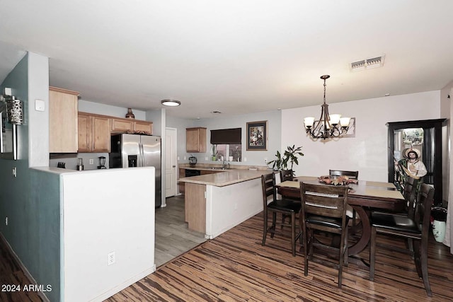 interior space featuring visible vents, a sink, a peninsula, stainless steel fridge with ice dispenser, and light countertops