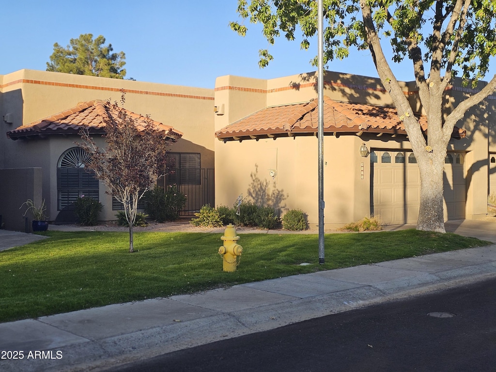 view of front of property featuring a tiled roof, a front yard, and stucco siding