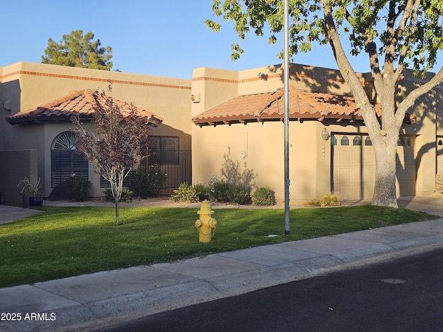 view of front of property featuring a tiled roof, a front yard, and stucco siding