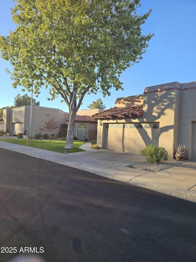 view of front of house with an attached garage, concrete driveway, and stucco siding