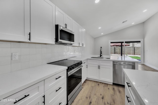 3926 E Coconino St, Phoenix, AZ 85044 - kitchen with stainless steel appliances, vaulted ceiling, light wood-style floors, white cabinetry, and backsplash
