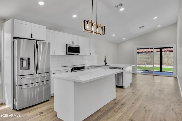 3926 E Coconino St, Phoenix, AZ 85044 - kitchen featuring appliances with stainless steel finishes, lofted ceiling, light wood-type flooring, a center island, and a peninsula