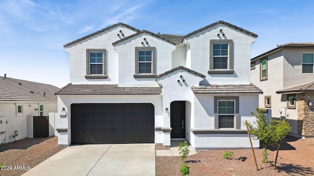 mediterranean / spanish-style home featuring a tiled roof, an attached garage, driveway, and stucco siding