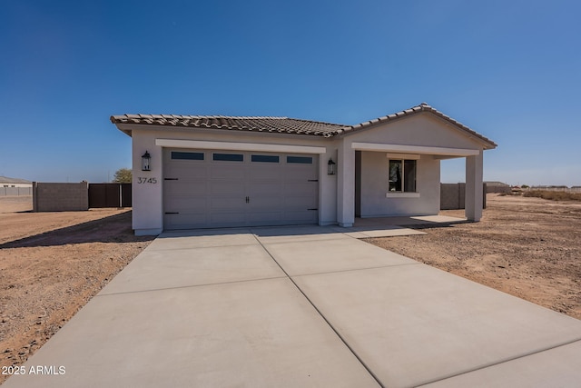 view of front of house with a tile roof, stucco siding, an attached garage, fence, and driveway