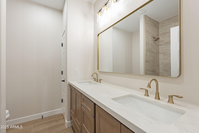 full bath featuring baseboards, a sink, toilet, and wood finished floors