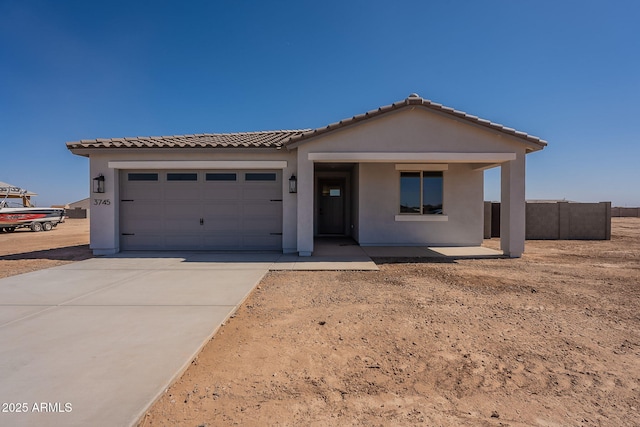 view of front of home featuring a garage, driveway, a tile roof, and stucco siding