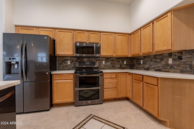 kitchen featuring tasteful backsplash, a towering ceiling, appliances with stainless steel finishes, and light tile patterned floors