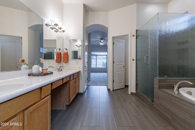 bathroom with ceiling fan, vanity, and plus walk in shower