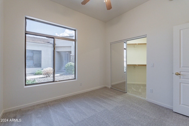 unfurnished bedroom featuring light carpet, multiple windows, ceiling fan, and a closet