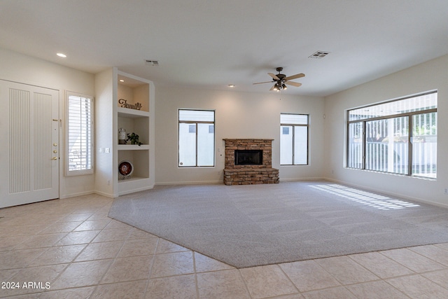 unfurnished living room featuring light carpet, built in features, ceiling fan, and a healthy amount of sunlight