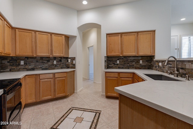 kitchen featuring black range with electric cooktop, backsplash, and sink