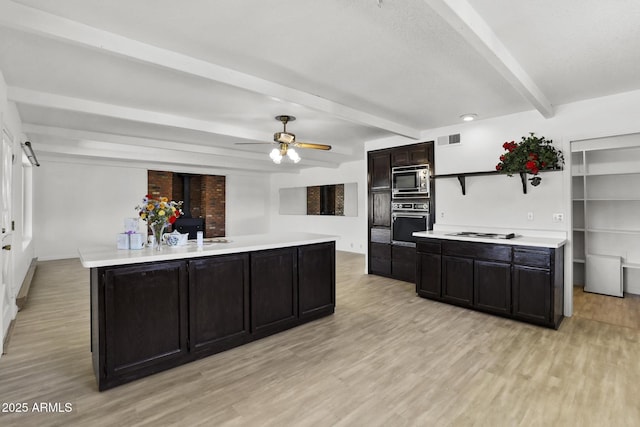 kitchen with built in microwave, a wood stove, white gas stovetop, black oven, and a kitchen island