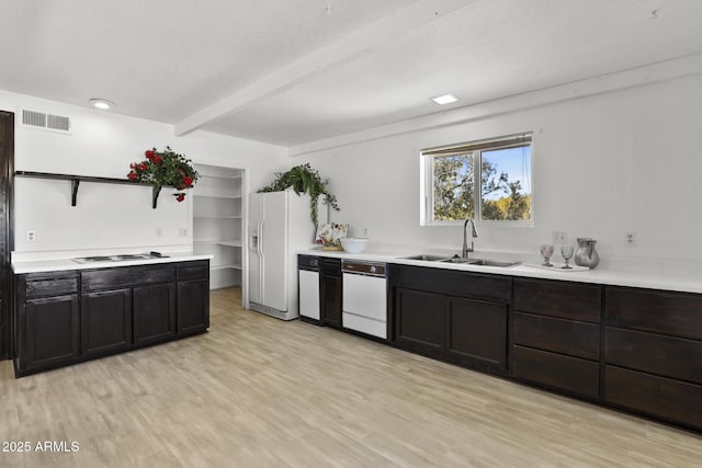 kitchen with beam ceiling, sink, white appliances, and light hardwood / wood-style flooring