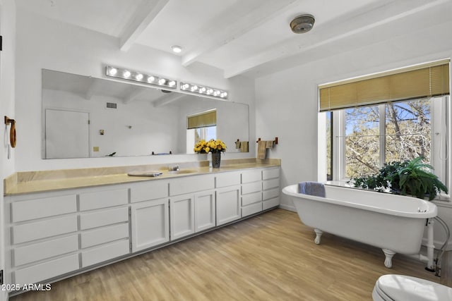 bathroom featuring vanity, wood-type flooring, a tub, and beamed ceiling