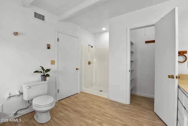 bathroom with hardwood / wood-style floors, beamed ceiling, a shower, vanity, and toilet