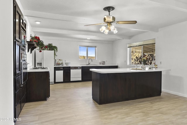 kitchen featuring dark brown cabinetry, sink, light hardwood / wood-style flooring, kitchen peninsula, and beamed ceiling