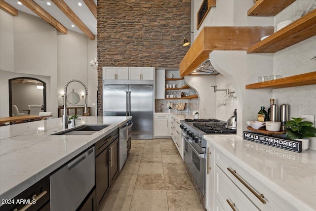 kitchen featuring white cabinets, beam ceiling, sink, high quality appliances, and light stone counters