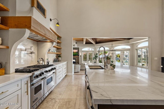 kitchen with french doors, white cabinetry, light stone countertops, and double oven range