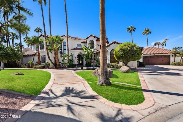 mediterranean / spanish home featuring a front yard and a garage