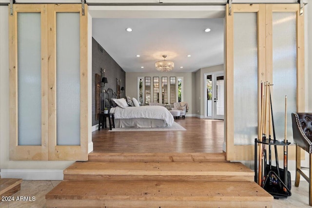 bedroom with a chandelier, light wood-type flooring, and a barn door