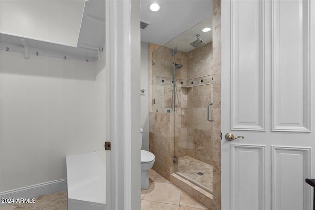 bathroom with toilet, tile patterned floors, and a shower with door