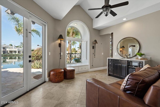 living room featuring vaulted ceiling, ceiling fan, a water view, and plenty of natural light