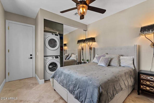 tiled bedroom featuring stacked washer / dryer and ceiling fan