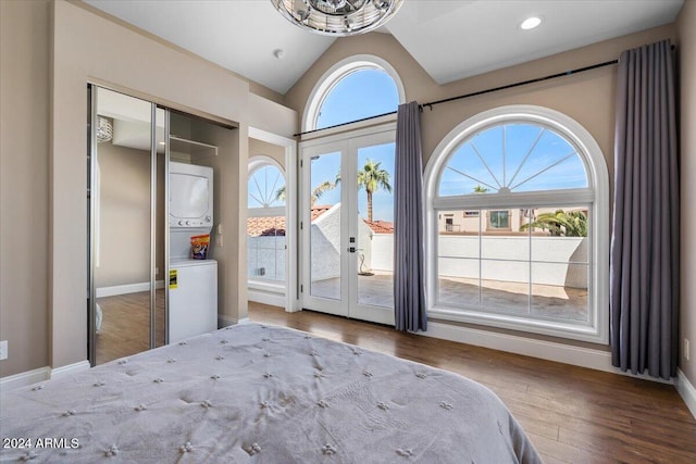 unfurnished bedroom featuring lofted ceiling, french doors, stacked washer and clothes dryer, hardwood / wood-style flooring, and a closet