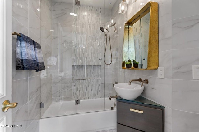 bathroom with tile walls, vanity, and combined bath / shower with glass door