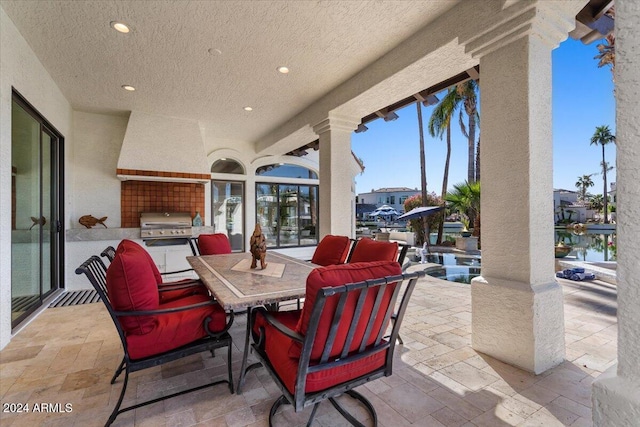 view of patio featuring an outdoor kitchen, grilling area, and a water view