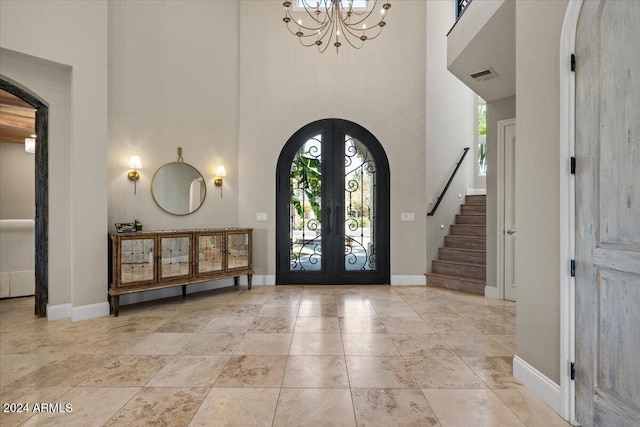 foyer entrance with french doors, a notable chandelier, and a high ceiling