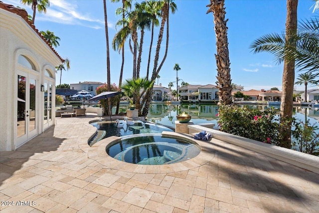 view of swimming pool featuring an in ground hot tub, a patio, french doors, and a water view