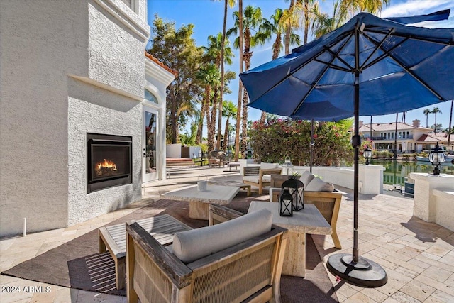 view of patio / terrace with an outdoor living space with a fireplace and a water view