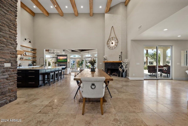 dining room with a towering ceiling, beamed ceiling, and a fireplace