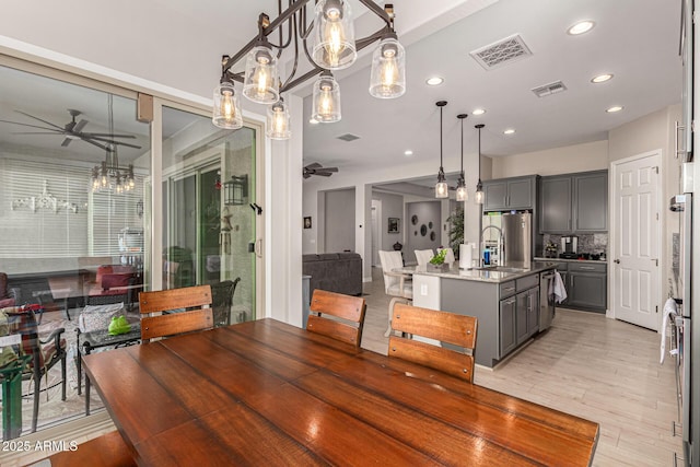 dining room with sink, ceiling fan, and light wood-type flooring