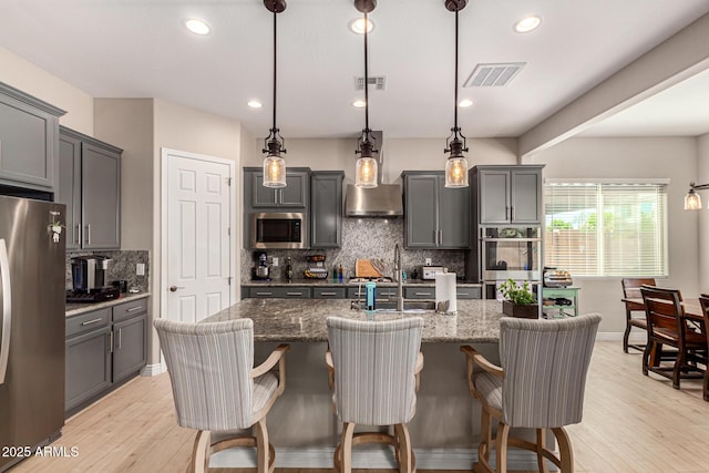 kitchen featuring pendant lighting, appliances with stainless steel finishes, and an island with sink