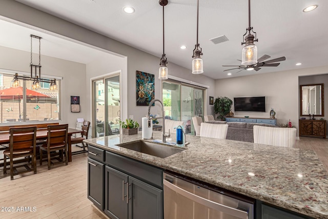 kitchen featuring light stone counters, stainless steel dishwasher, sink, and pendant lighting